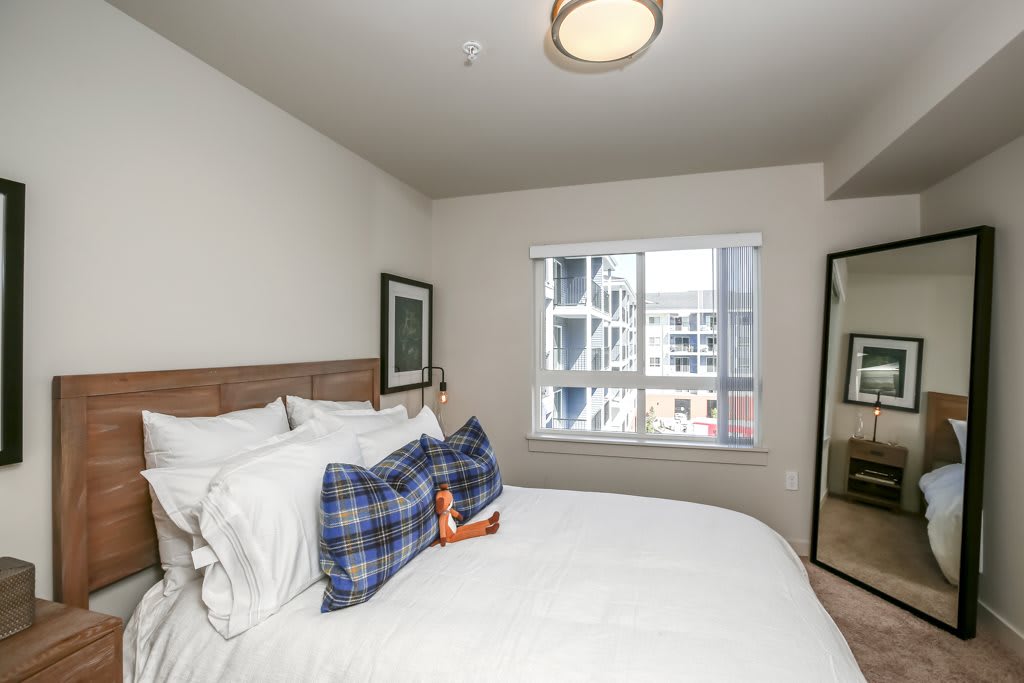 A cozy bedroom with a neatly made bed, featuring large pillows and a window with a view of a building outside.