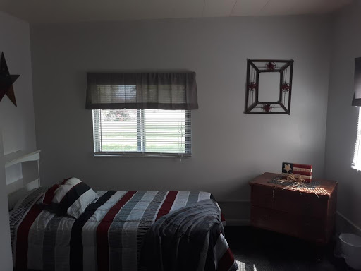 A cozy bedroom featuring a neatly made bed, a desk, and natural light coming through the window.
