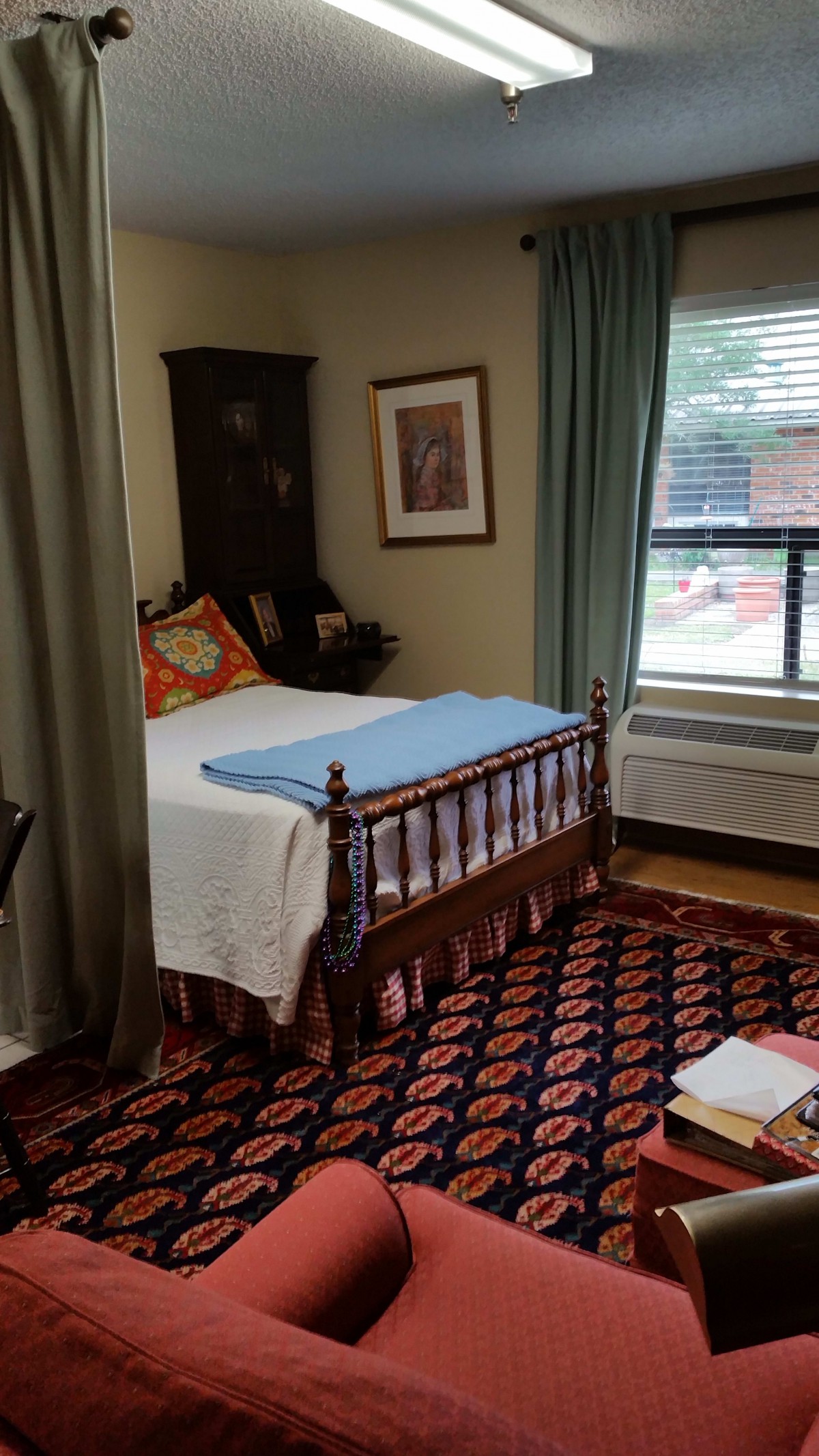 A cozy bedroom with a wooden bed, patterned carpet, and large window.