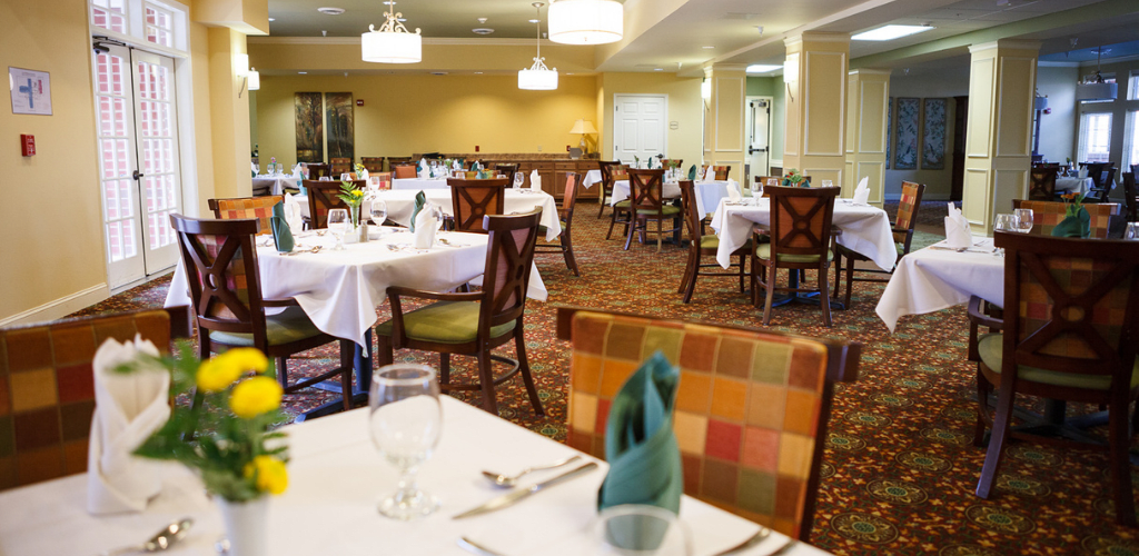An elegant dining room with neatly arranged tables and chairs, set for guests.