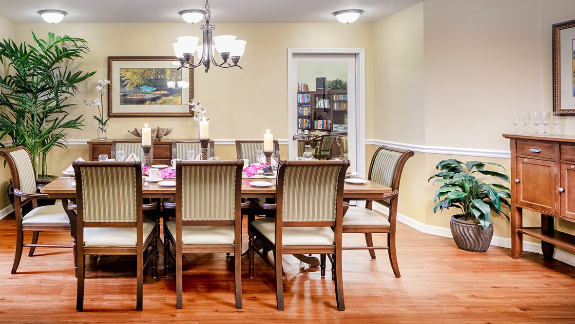 A beautifully decorated dining room with a long wooden table and chairs, adorned with candles and elegant decor.