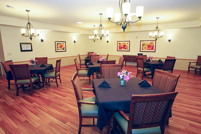 A cozy dining room with neatly arranged tables and elegant chandeliers.
