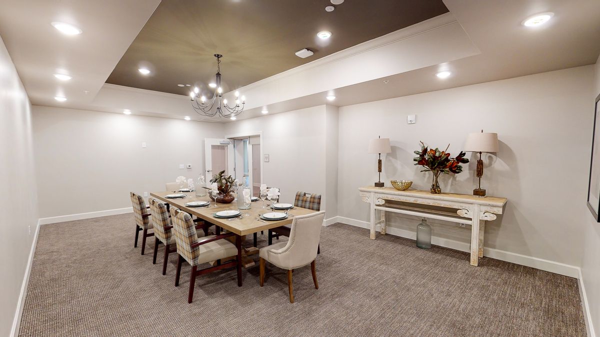 A modern dining room with a large table and elegant seating, complemented by a stylish chandelier and minimalist decor.