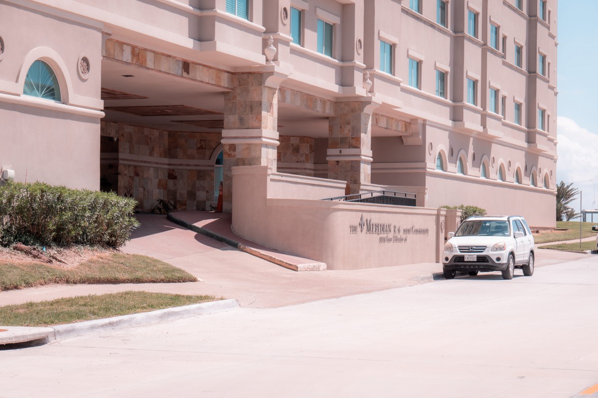 The entrance of a hotel with a parked vehicle outside.