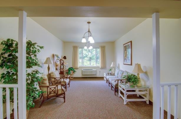 A cozy living room with comfortable seating, indoor plants, and natural light coming through a large window.