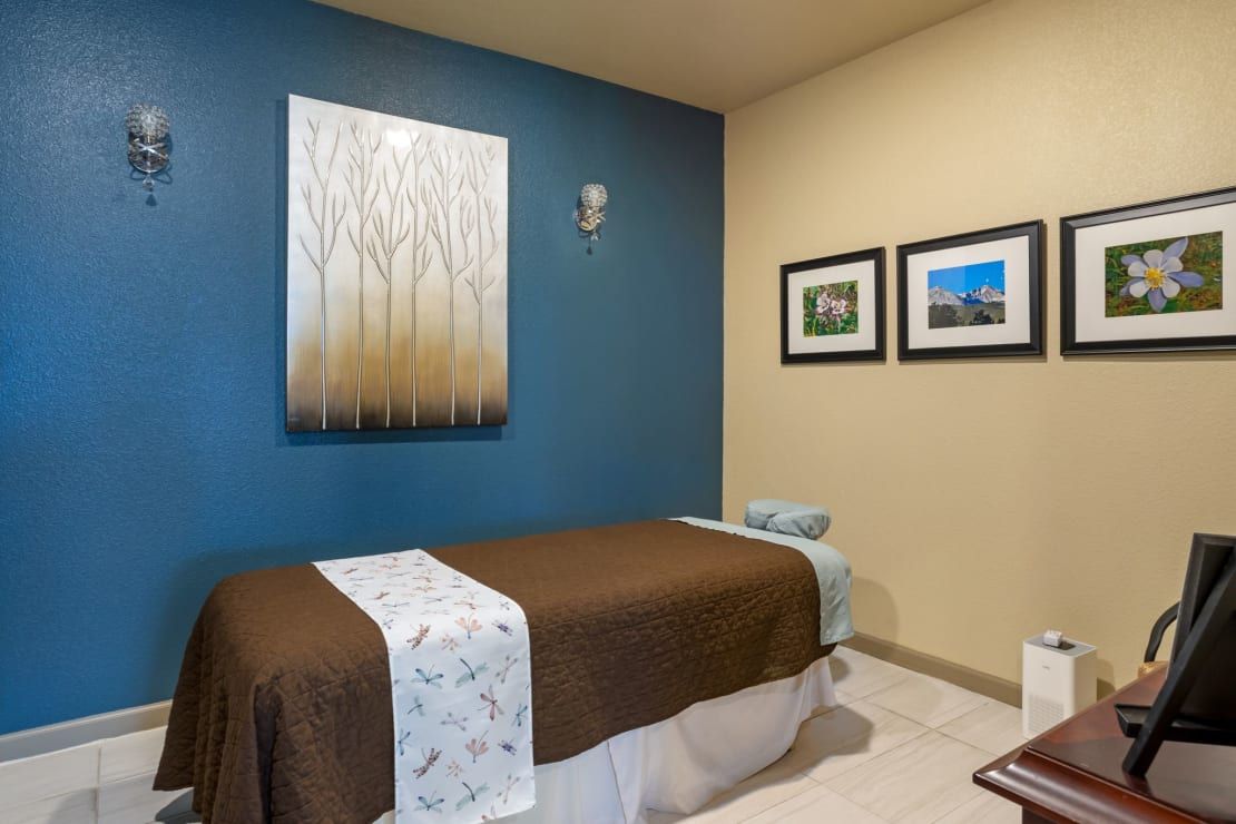 A tranquil spa room featuring a massage table and calming wall art.