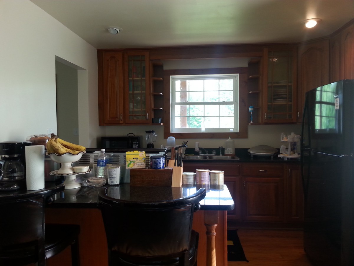 A cozy kitchen with wooden cabinets and a variety of kitchenware on the countertop.