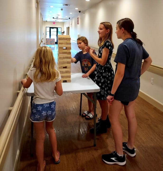 A group of children playing a game of Jenga indoors in a hallway.