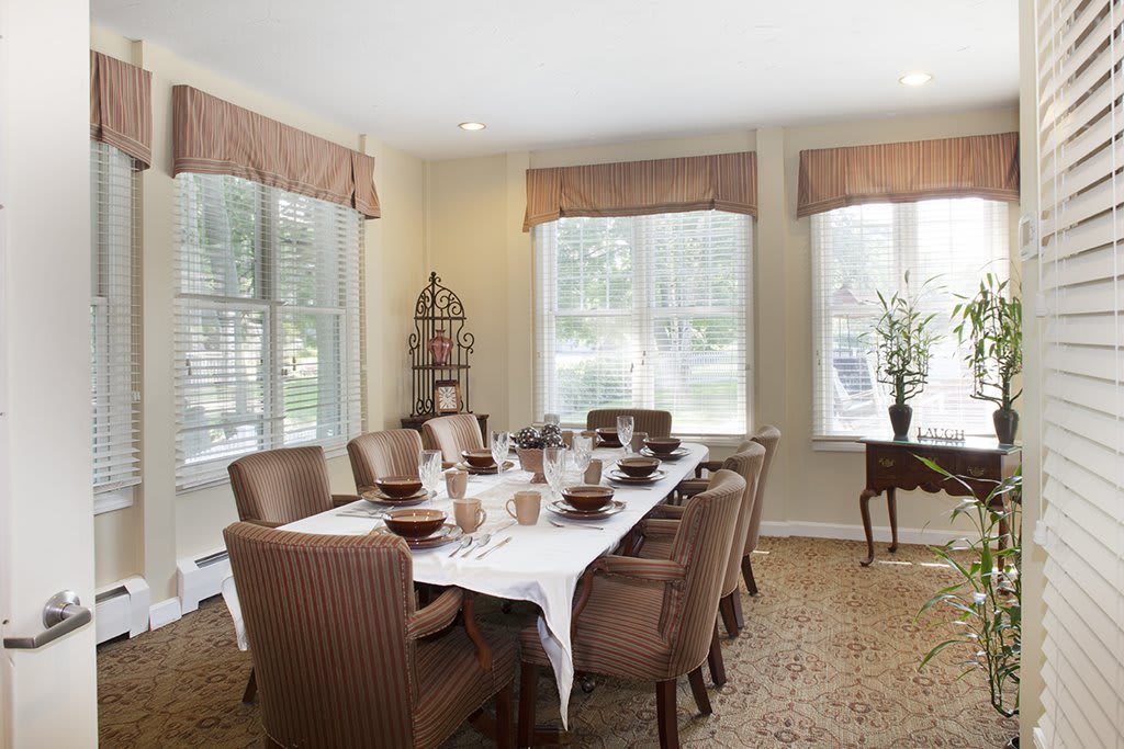 A well-lit dining room with a large table set for a meal, surrounded by chairs and adorned with elegant decor.
