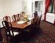 A dining room with a large wooden table and matching chairs, decorated with a centerpiece on the table.