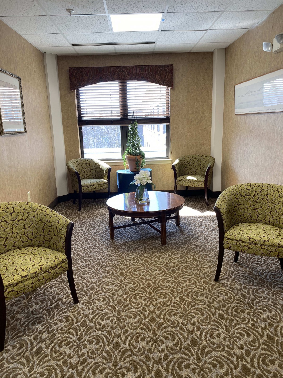 A cozy waiting room with four chairs, a round table, and a window view.