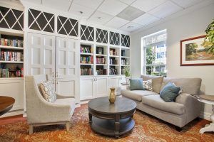 A cozy living room with bookshelves, a comfortable sofa, and an armchair around a coffee table.