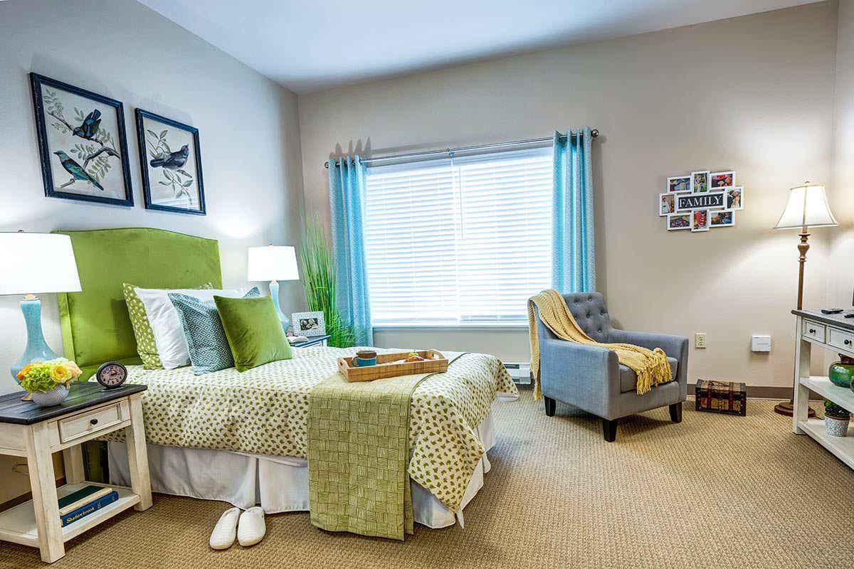 A cozy bedroom with green accents and a comfortable armchair.
