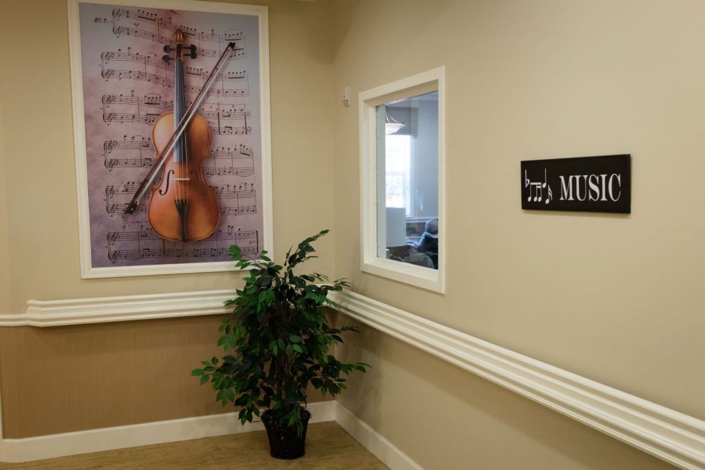 A hallway with a violin artwork and a potted plant next to a window.