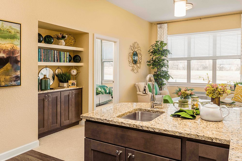 A modern kitchen with a central island and decorative elements, featuring plants and warm lighting.