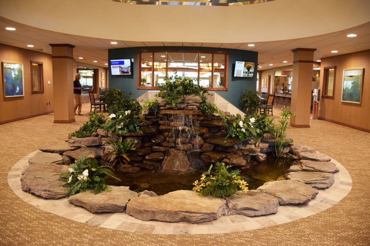 A beautifully designed indoor fountain surrounded by plants in a lobby area.