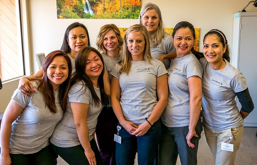 A group of women posing and smiling in matching attire indoors.