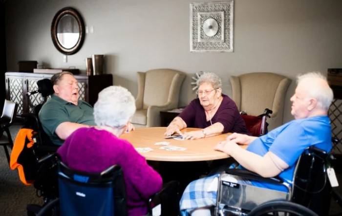 A group of elderly individuals sitting around a table engaging in conversation.