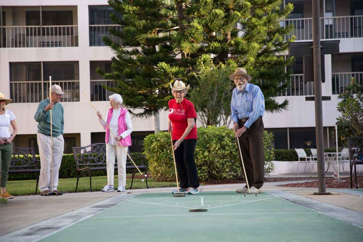 A group of seniors playing shuffleboard outdoors.