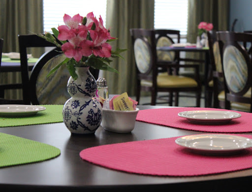 A beautifully arranged dining table with colorful placemats and a floral centerpiece.
