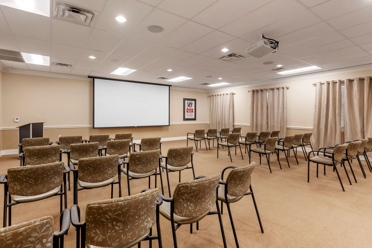 A well-arranged conference room with multiple chairs facing a projector screen.