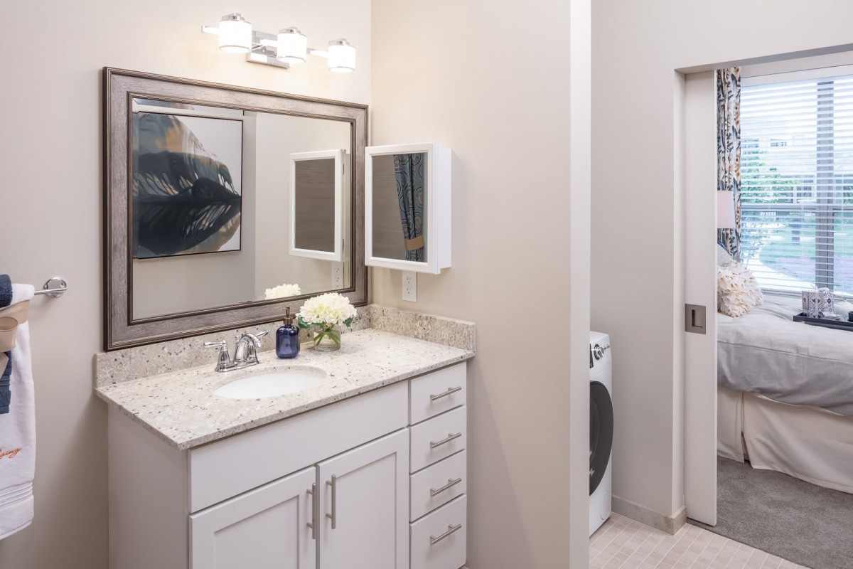 A modern bathroom with a white vanity and a connected laundry area.