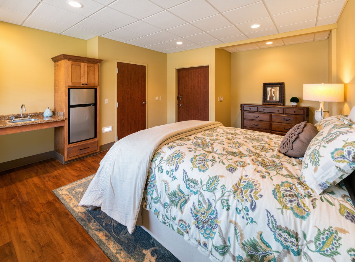 A cozy bedroom with a floral bedspread and wooden furnishings.