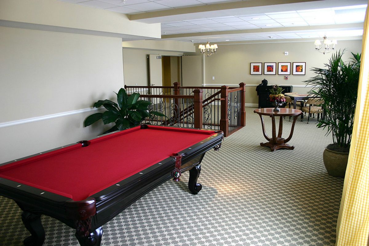 A stylish game room featuring a pool table with red felt and elegant decor.