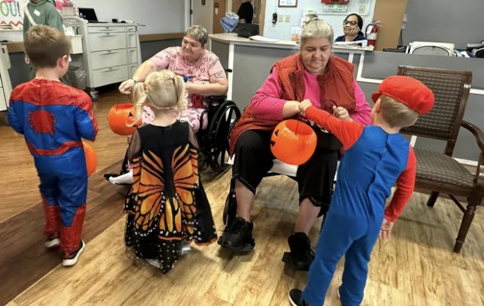 Children in Halloween costumes interacting with seniors during a community event.