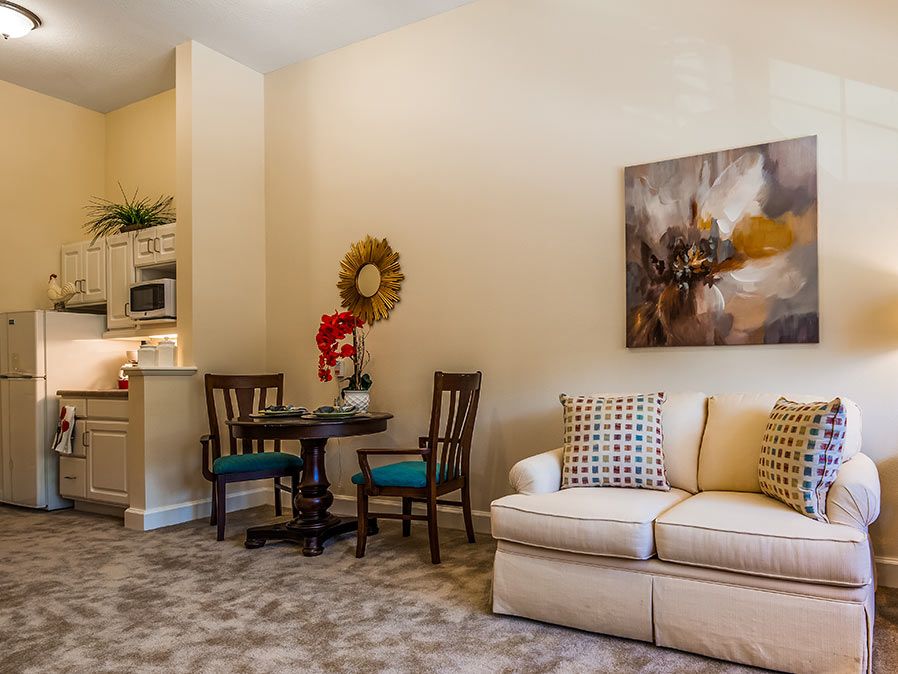 A cozy living room with a sofa, dining set, and wall art.