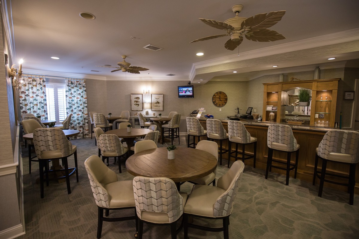 A cozy lounge area with round tables, comfortable chairs, and a bar.