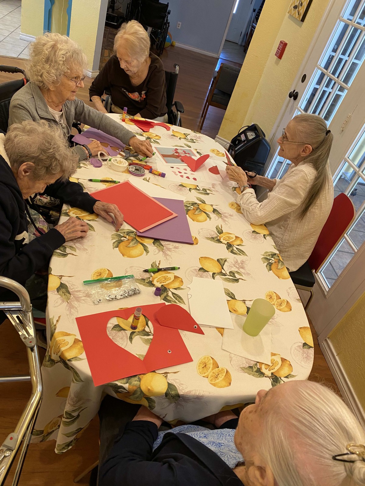 A group of elderly people sitting around a table engaged in arts and crafts activities.