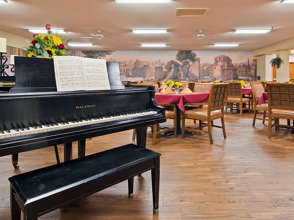 A dining area with a piano and tables set for service.