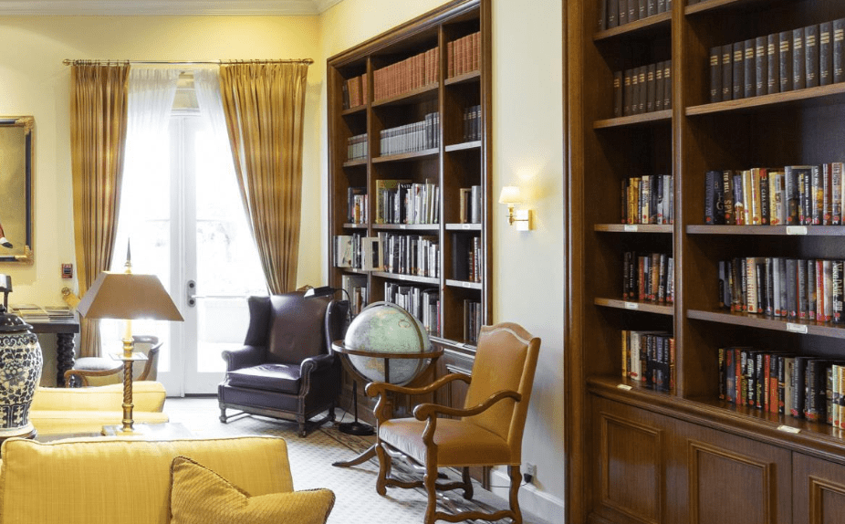 A cozy library with tall bookshelves, a globe, and comfortable chairs.