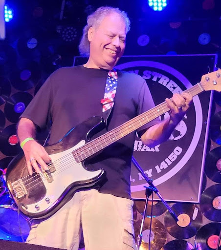 A musician joyfully playing the bass guitar during a live performance.