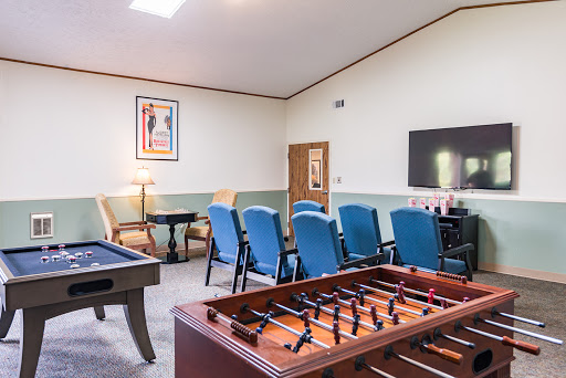 A cozy game room featuring a foosball table, a pool table, comfortable blue seating, and a TV for entertainment.