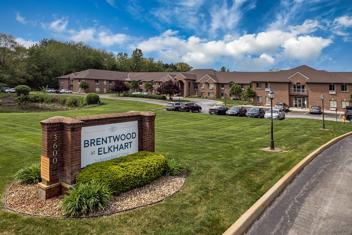 A view of a building with a sign reading 'Brentwood Elkhart,' surrounded by well-maintained grass and trees under a partly cloudy sky.