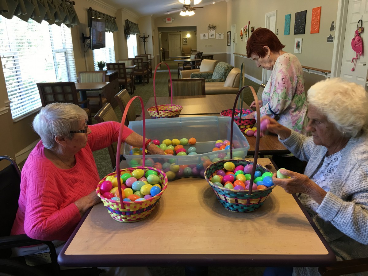 Seniors engaging in a crafting activity with colorful plastic eggs at a community center.