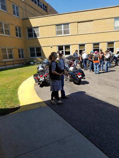 A group of people gathered outside a building, with motorcycles parked nearby.
