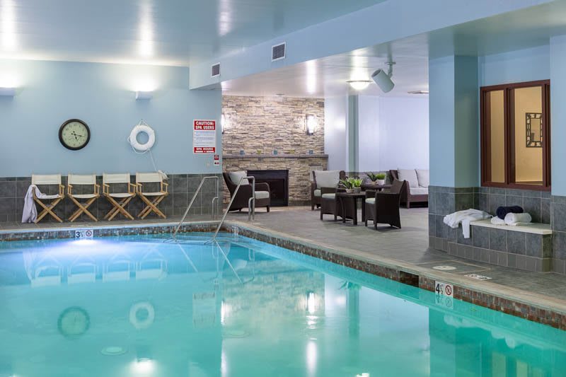 A tranquil indoor swimming pool with comfortable seating and loungers.