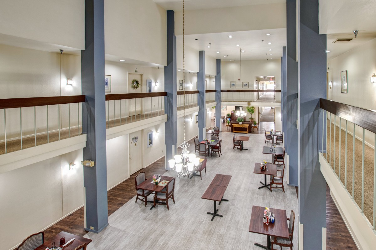A spacious, modern restaurant interior featuring high ceilings and elegantly arranged dining tables.
