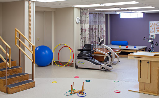 A rehabilitation gym featuring various exercise equipment and colorful accessories for therapy.
