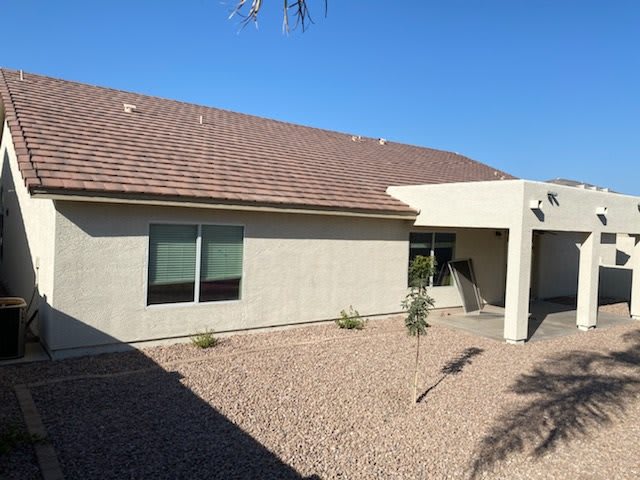 A single-story house with a desert landscape and covered entryway.