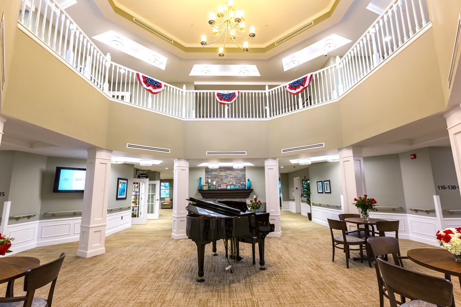 A spacious atrium with a grand piano and elegant balcony in a well-lit interior.