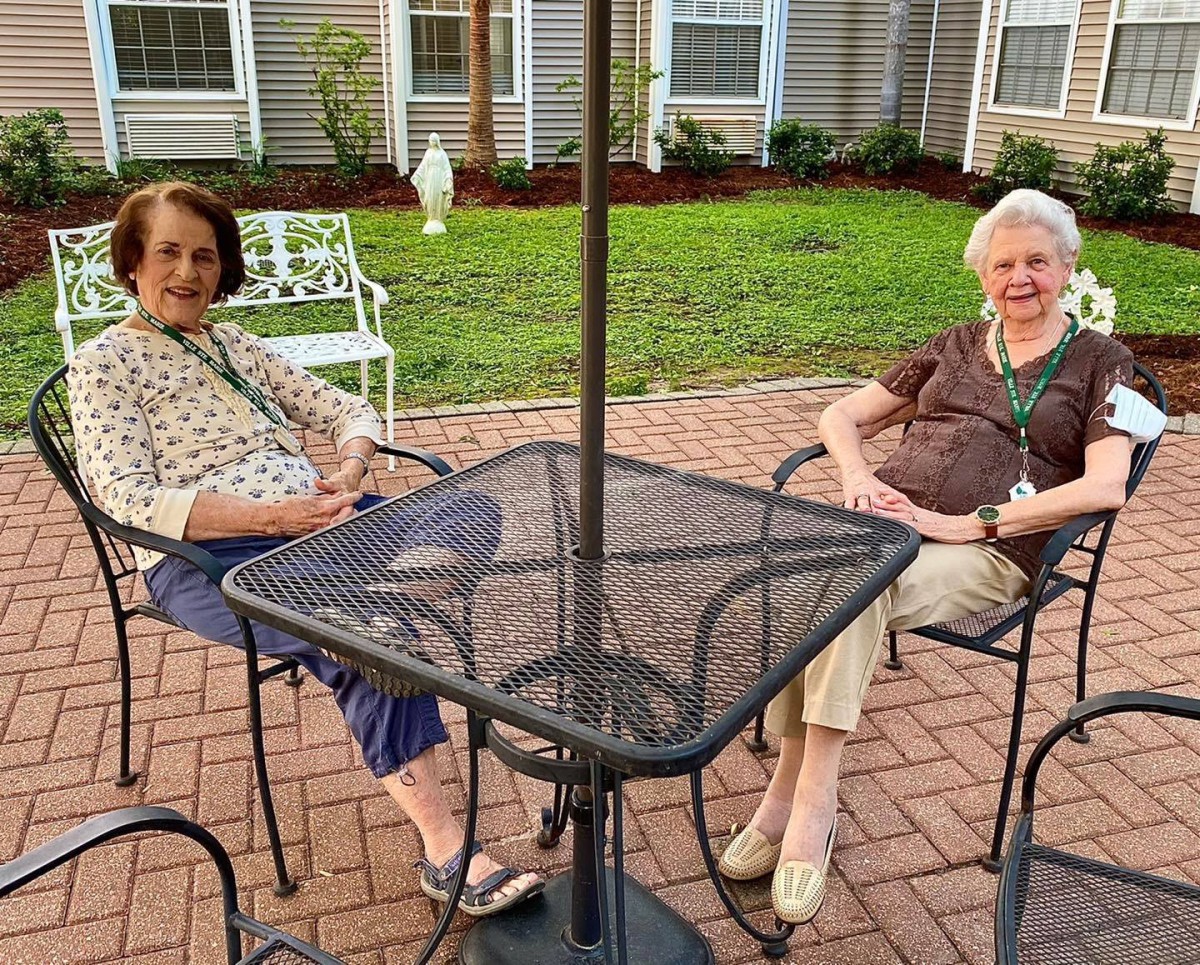 Two elderly women sitting and relaxing on a patio.