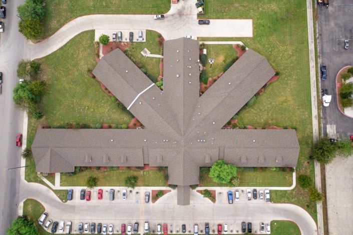 Aerial view of a symmetrical building with surrounding parking area.