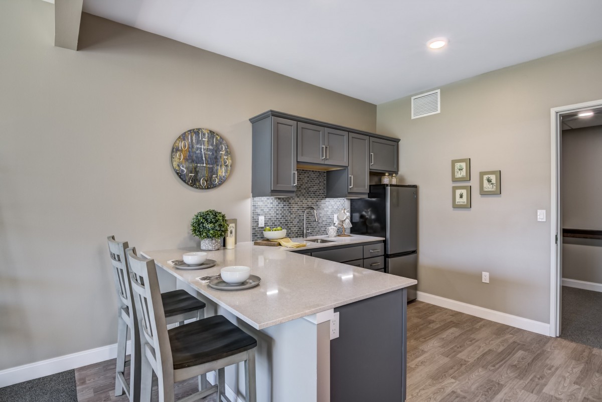 A modern kitchen interior with a sleek design and bar stools at the countertop.