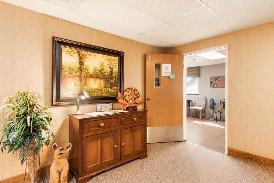An inviting reception area featuring a wooden cabinet, a decorative painting, and warm lighting.