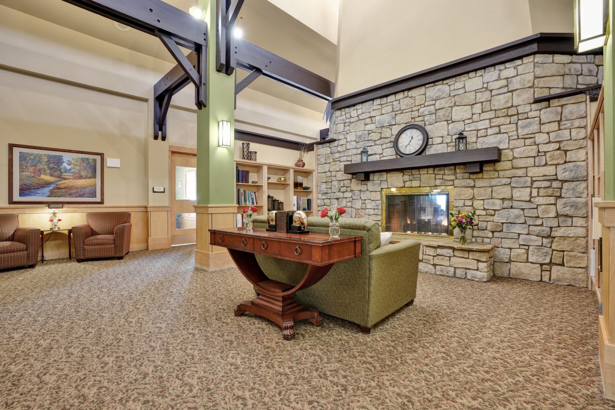 A cozy living room interior with a stone fireplace, comfortable seating, and decorative elements.