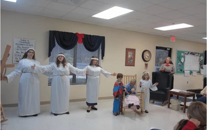 Children performing a nativity scene indoors, dressed in holiday costumes.